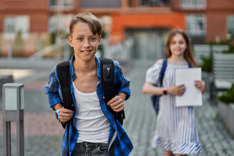 Handsome little boy and pretty kid girl going school with backpa